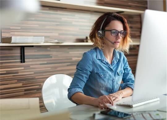 Woman wearing Leitner wireless headset using computer